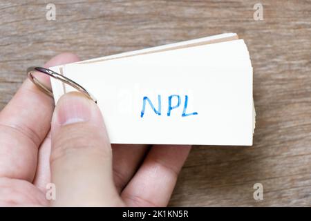 Hand halten Flash-Karte mit Handschrift in Wort NPL (Abkürzung für Non Performing Loan, Non-Patent Literature) auf Holzhintergrund Stockfoto