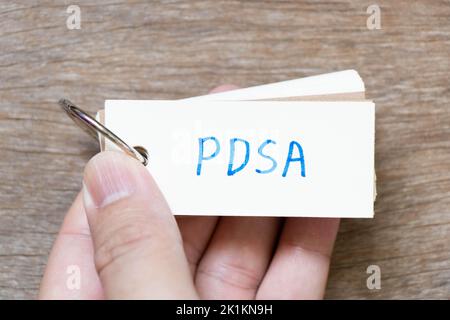 Hand halten Flash-Karte mit Handschrift in Wort PDSA (Abkürzung von Plan do study Act) auf Holz Hintergrund Stockfoto