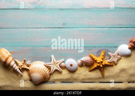 Vacations and summer time concept with starfish and sea shells on a turquoise wooden table with sand Stockfoto