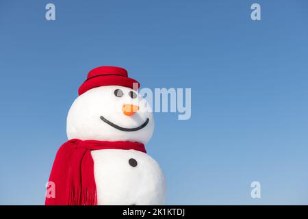 Lustiger Schneemann in stilvollem roten Hut und rotem Skalpenknopf Auf blauem Himmel Hintergrund Stockfoto