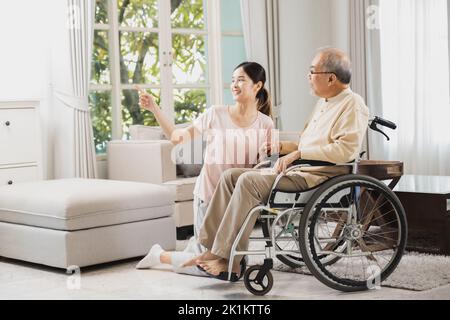 Senior mit schöner Tochter, alter Mann sitzt im Rollstuhl im Haus, kümmern ältere Patienten und Freunde zu Hause sein Stockfoto