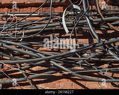 Externe Telekommunikationskabel und -Drähte hängen zufällig an der Ziegelwand Stockfoto