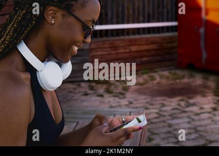 Nahaufnahme einer schönen afroamerikanischen Frau mit einem Smartphone. Stockfoto