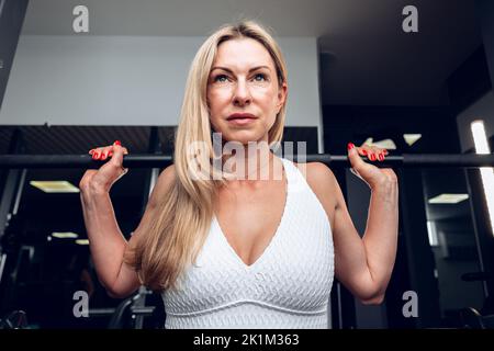 Fitness-Frau mittleren Alters macht hockende Übung in einem Fitnessstudio Stockfoto