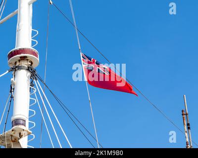 Roter Fähnrich, der über einem Boot entlang des Docks in Großbritannien fliegt Stockfoto