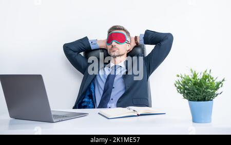 Müde Unternehmer entspannen in Schlafmaske am Arbeitsplatz Stockfoto