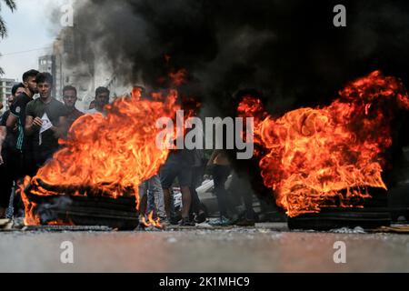 Beirut, Libanon. 19. September 2022. Libanesische Aktivisten stehen hinter brennenden Reifen in der Nähe des Justizpalastes, wo sie sich versammelten, um die Freilassung von zwei Personen zu fordern, die festgenommen wurden, nachdem sie letzte Woche eine lokale Bank mit einer Pistolenpistole stürmten, um einem Einleger zu helfen, ihre Ersparnisse einzutreiben. Libanesische Banken haben die meisten Einleger aufgrund des wirtschaftlichen Zusammenbruchs des Landes aus ihren Ersparnissen ausgeschlossen. Quelle: Marwan Naamani/dpa/Alamy Live News Stockfoto