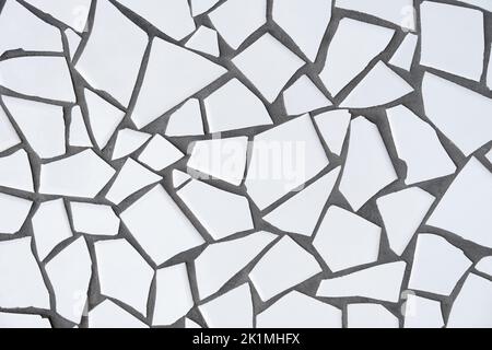 Fliesen Mosaik, nahtlose Muster. Stück weiße zerbrochene Keramikfliesen an einer Betonwand. Stockfoto