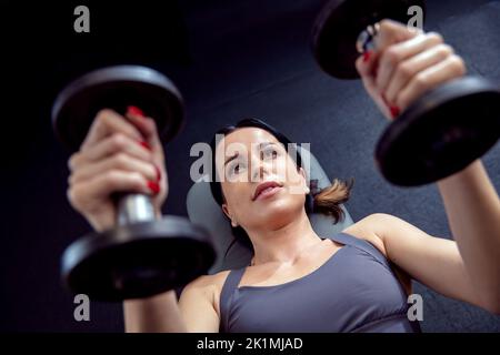 Fit und attraktive Brünette Workouts mit Hanteln in den Händen Stockfoto