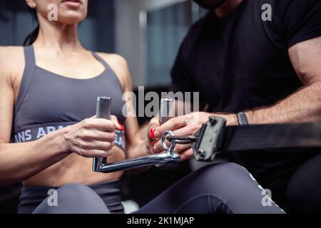 Fit junge Frau Übungen mit Personal Trainer im Fitnessstudio Stockfoto