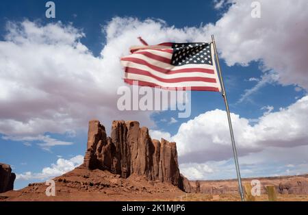 Die Flagge der Vereinigten Staaten von Amerika fliegt in der Sonne vor einem Felsen im Monument Valley. Stockfoto