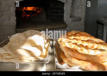 Traditionelles Brot in einer türkischen Bäckerei während des Ramadan - Ramazan Pidesi, in einem Steinofen. Stockfoto