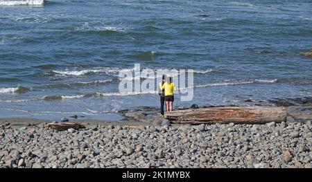 Ein junges Paar beobachtet die Brandung von einem felsigen Strand an der Pazifikküste von Oregon in der Nähe des Dorfes Seal Rock, Oregon. Stockfoto