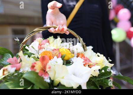 Korb mit Blumenstrauß in den Händen Stockfoto