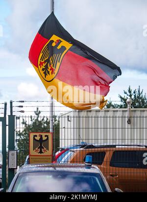 Lubmin, Deutschland. 19. September 2022. Die Flagge der Bundesrepublik Deutschland mit dem Wappen, einem schwarzen Adler auf gelbem Hintergrund, fliegt am Halbmast im Büro der Bundespolizei in Lubmin als Zeichen der Trauer nach dem Tod der britischen Königin Elizabeth II. Am 19. September wird die Beerdigung in London im Beisein zahlreicher internationaler Staatsoberhäupter stattfinden. Quelle: Stefan Sauer/dpa/Alamy Live News Stockfoto