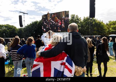 London, Großbritannien. 19. September 2022. Zwei Menschen umarmen sich im Hyde Park, während sie das Begräbnis von Königin Elizabeth II von den Großbildschirmen aus sehen.Quelle: Massimiliano Donati/Alamy Live News Stockfoto