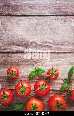 Frische Tomaten und Basilikum auf Holztisch, Kochhintergrund, Draufsicht, Kopierraum Stockfoto