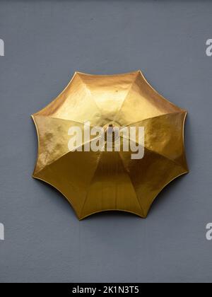 Zürich, Schweiz - 10. Juli 2022: Historisches Modell eines goldenen Regenschirms an der Wand der ehemaligen Regenschirmfabrik am Münsterhof in Zürich, Schweiz Stockfoto