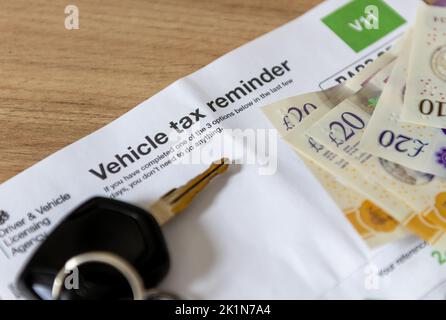 Ein Erinnerungsdokument über die Fahrzeugsteuer eines Schreibtisches mit Autoschlüssel und Geld. Stockfoto