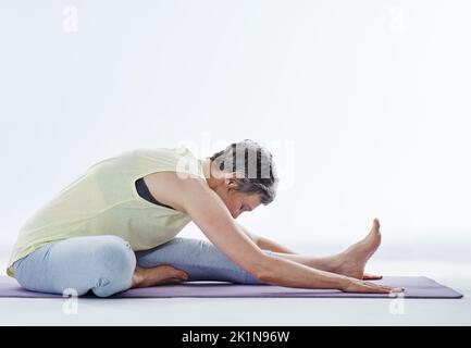 Unterschätzen Sie niemals die Bedeutung eines guten Aufwärmpuls. Ganzkörperaufnahme einer attraktiven Frau, die sich vor dem Yoga dehnt. Stockfoto