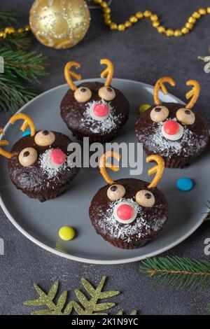 Hausgemachte Weihnachts-Cupcakes Weihnachtsmann Rentiere auf grauem Hintergrund, Fun-Idee für Kinderparty Stockfoto