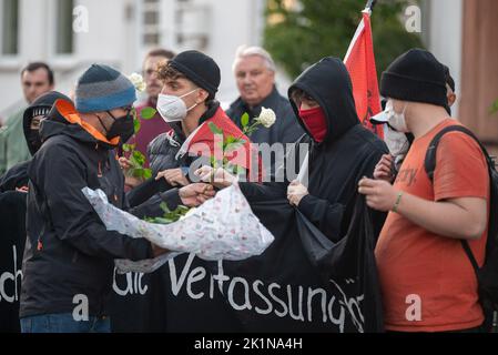 Saarlouis, Deutschland. 19. September 2022. Ein Teilnehmer an der Gedenkkundgebung für Samuel Yeboah, einen ghanaischen Asylbewerber, der 1991 bei einem Brandanschlag getötet wurde, verteilt Blumen, die an einem Gedenkstein angebracht werden. Mitte November beginnt der Prozess gegen einen 51-jährigen Mann vor dem Oberlandesgericht Koblenz - unter anderem wegen Mordes. Er soll in der Nacht vom 18. Auf den 19. September 1991 in der Saarlouiser Straße das Feuer in der Unterkunft der Asylbewerber angezündet haben. Quelle: Harald Tittel/dpa/Alamy Live News Stockfoto