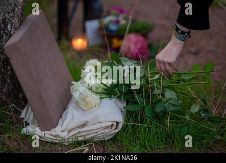 Saarlouis, Deutschland. 19. September 2022. Ein Teilnehmer der Gedenkkundgebung für den ghanaischen Asylbewerber Samuel Yeboah, der 1991 bei einem Brandanschlag getötet wurde, legt Blumen an einen Gedenkstein. Mitte November beginnt der Prozess gegen einen 51-jährigen Mann vor dem Oberlandesgericht Koblenz - unter anderem wegen Mordes. Er soll in der Nacht vom 18. Auf den 19. September 1991 in der Saarlouiser Straße das Feuer in der Unterkunft der Asylbewerber angezündet haben. Quelle: Harald Tittel/dpa/Alamy Live News Stockfoto