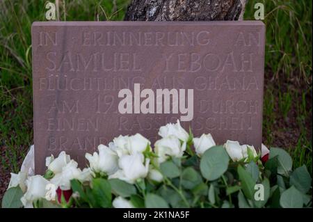 Saarlouis, Deutschland. 19. September 2022. Die Teilnehmer der Gedenkkundgebung für den ghanaischen Asylbewerber Samuel Yeboah, der 1991 bei einem Brandanschlag getötet wurde, legten Blumen an einen Gedenkstein. Mitte November beginnt der Prozess gegen einen 51-jährigen Mann vor dem Oberlandesgericht Koblenz - unter anderem wegen Mordes. Er soll in der Nacht vom 18. Auf den 19. September 1991 in der Saarlouiser Straße das Feuer in der Unterkunft der Asylbewerber angezündet haben. Quelle: Harald Tittel/dpa/Alamy Live News Stockfoto