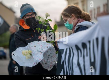 Saarlouis, Deutschland. 19. September 2022. Ein Teilnehmer an der Gedenkkundgebung für Samuel Yeboah, einen ghanaischen Asylbewerber, der 1991 bei einem Brandanschlag getötet wurde, verteilt Blumen, die an einem Gedenkstein angebracht werden. Mitte November beginnt der Prozess gegen einen 51-jährigen Mann vor dem Oberlandesgericht Koblenz - unter anderem wegen Mordes. Er soll in der Nacht vom 18. Auf den 19. September 1991 das Feuer in der Unterkunft der Asylbewerber angezündet haben. Quelle: Harald Tittel/dpa/Alamy Live News Stockfoto