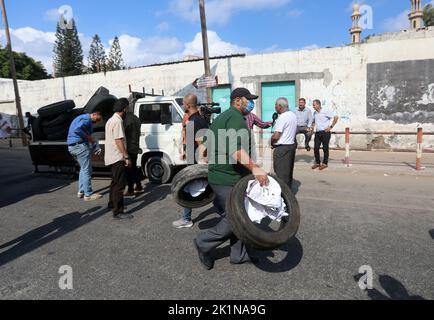 Gaza, Palästina. 19. September 2022. Ein Protestler trägt Reifen, um während einer Demonstration vor dem Hauptquartier des Hilfswerks der Vereinten Nationen (UNRWA) für Palästina-Flüchtlinge in Gaza zu verbrennen. Palästinensische Gruppen organisierten einen Protest gegen das Werk- und Hilfswerk der Vereinten Nationen (UNRWA) und forderten, dass das UNRWA die palästinensischen Häuser wiederaufbauen sollte, die während der Kämpfe zwischen Israel und Gaza im Jahr 2014 zerstört wurden. (Foto von Ahmed Zakot/SOPA Images/Sipa USA) Quelle: SIPA USA/Alamy Live News Stockfoto