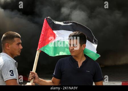 Gaza, Palästina. 19. September 2022. Ein Protestler hält eine palästinensische Flagge während einer Demonstration vor dem Hauptquartier des UN-Hilfswerks für palästinensische Flüchtlinge. Palästinensische Gruppen organisierten einen Protest gegen das Werk- und Hilfswerk der Vereinten Nationen (UNRWA) und forderten, dass das UNRWA die palästinensischen Häuser wiederaufbauen sollte, die während der Kämpfe zwischen Israel und Gaza im Jahr 2014 zerstört wurden. (Foto von Ahmed Zakot/SOPA Images/Sipa USA) Quelle: SIPA USA/Alamy Live News Stockfoto