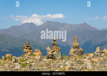 Die Steinpyramiden werden auf einem Bergpass errichtet. Im Hintergrund schöne Gipfel der majestätischen Berge Stockfoto