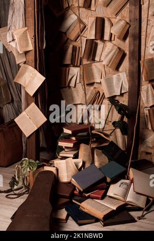 Bücher liegen auf dem Boden und hängen an den Wänden in einem dunklen Raum. Retro Stockfoto