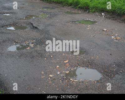 Löcher auf einer mit Wasser gefüllten Feldstraße Stockfoto