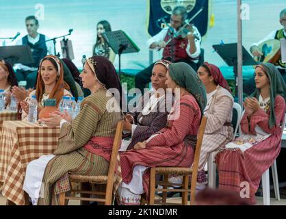 Zyprioten in traditioneller Kleidung beobachten Darsteller beim Statos-Agios Fotios Rural Festival, Region Paphos, Zypern. Stockfoto