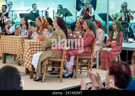 Zyprioten in traditioneller Kleidung beobachten Darsteller beim Statos-Agios Fotios Rural Festival, Region Paphos, Zypern. Stockfoto