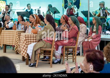 Zyprioten in traditioneller Kleidung beobachten Darsteller beim Statos-Agios Fotios Rural Festival, Region Paphos, Zypern. Stockfoto