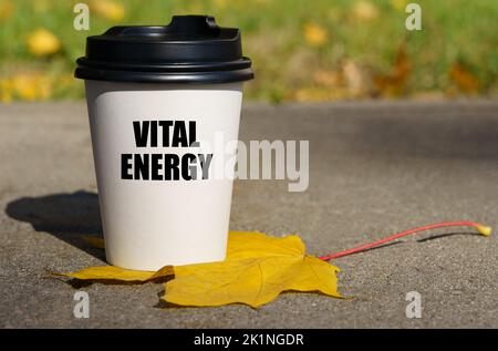 Auf einem gelben Ahornblatt steht eine Tasse Kaffee, auf dem geschrieben ist - Lebensenergie. Motivationskonzept Stockfoto