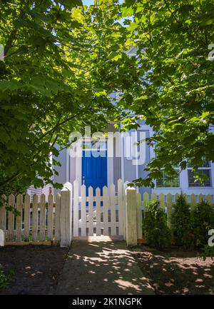 Eingang zu einem Haus durch einen schönen Garten mit bunten Blumen. Pflanzen und Blumen in Töpfen vor einer Haustür, die zum Eingang eines Hauses führt. Vorderseite von Stockfoto