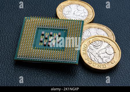 Große Computer-Chip-CPU und britische Pfund-Münzen. Konzept für Mikrochips und Geld. Makro, selektiver Fokus. Stockfoto