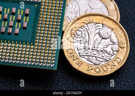 Große Computer-Chip-CPU und britische Pfund-Münzen. Konzept für Mikrochips und Geld. Makro, selektiver Fokus. Stockfoto