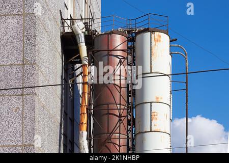 Industrierohre vom Ende des Gebäudes, rostige alte Rohre an der Seite der Fassade des Hauses Stockfoto