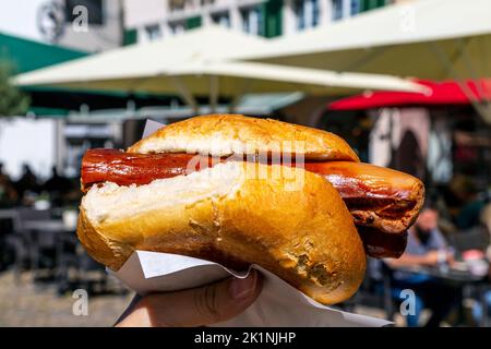 Deutsche Wurst auf knusprigem Brötchen aus Meier's Wurststand auf dem Münstermarkt auf dem Münsterplatz, Freiburg im Breisgau, Deutschland Stockfoto