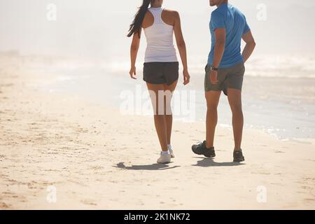 Waren zusammen dabei. Rückansicht eines jungen Paares, das in Sportkleidung am Strand läuft. Stockfoto