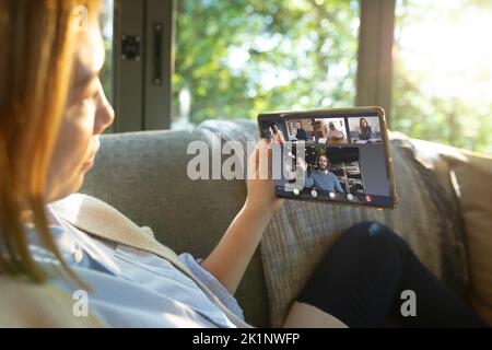 Asiatische Frau mit blonden Haaren Videokonferenzen mit Kollegen über digitales Tablet auf dem Sofa Stockfoto