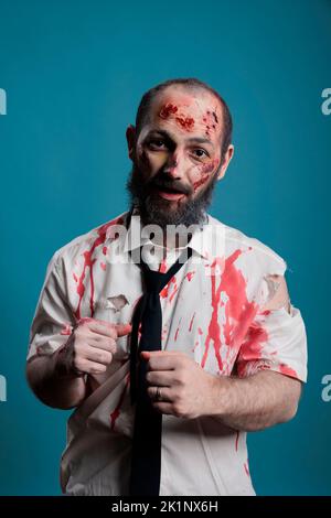 Portrait of Brain eating Zombie im Studio mit blutigen Wunden und schmutzigen Narben, handeln gefährlich und tödlich. Unheimliches apokalyptisches Monster, das böse und aggressiv aussieht, verrückter Thriller-Teufel. Stockfoto