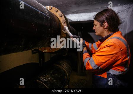 Arbeiter, der Wasserleitung im technischen Tunnel installiert, Nahaufnahme Stockfoto