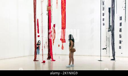Frauen in Gesichtsmasken sehen die Installationskunst der chilenischen Cecilia Vicuña im Guggenheim Museum, Manhattan, NYC, USA Stockfoto