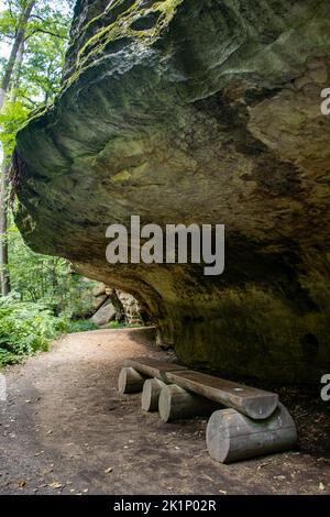 Holzbänke auf dem Rastplatz unter dem Felsüberhang Stockfoto