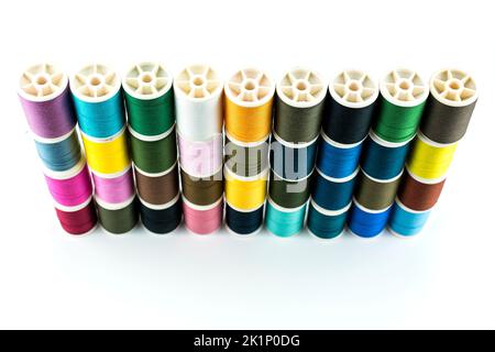 Fadenröhrchen für Nähgarn haben viele Farben und sind auf weißem Hintergrund platziert. Stockfoto